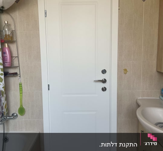 דלת לבנה בחדר אמבטיה עם ידית כסופה